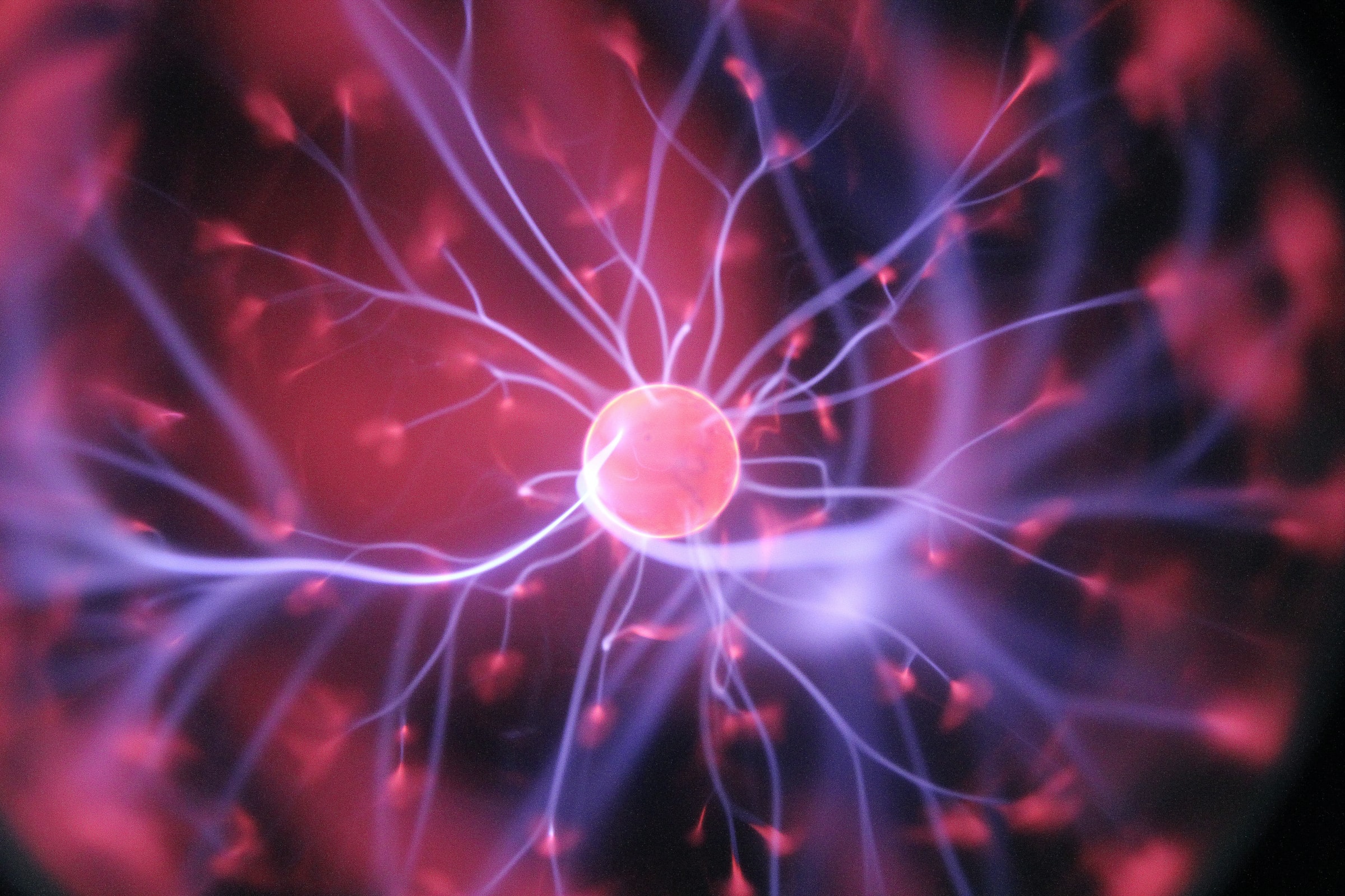 A plasma ball emits glowing purple and pink tendrils of light from its central sphere, creating patterns reminiscent of exosome activity, radiating outward against a dark background.