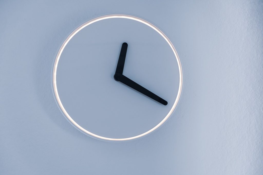 A minimalist wall clock with a white face, no numbers, and black hour and minute hands set to 10:10, mounted on a light-colored wall—perfect for those who want to recognize intuition in their daily surroundings.